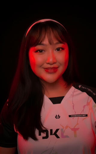 A portrait of ALYA, Talent Manager for DKLT Designs, smiling and wearing an E-sports jersey.