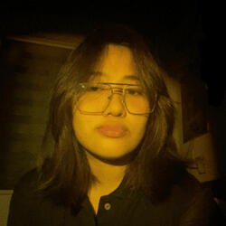 Portrait of KYOMI, a female DKLT Designs team member, with yellow lighting and large glasses.