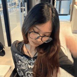 Portrait of SAM, a female DKLT Designs team member, wearing glasses and looking down.